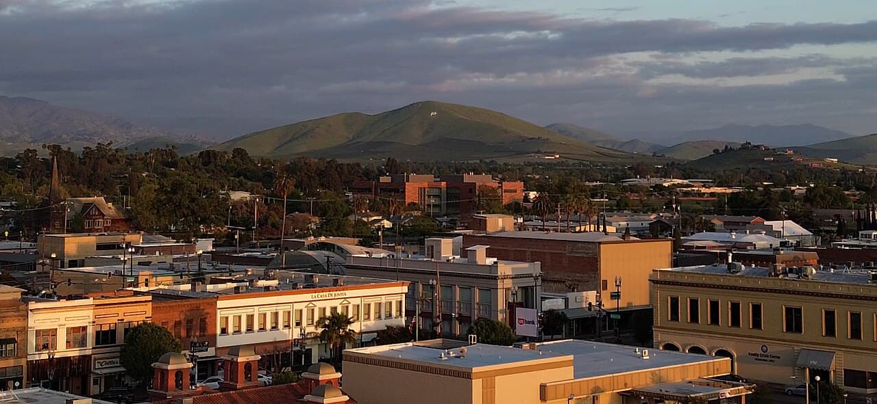 Downtown Porterville buildings in evening light beneath a green hill marked with a P.