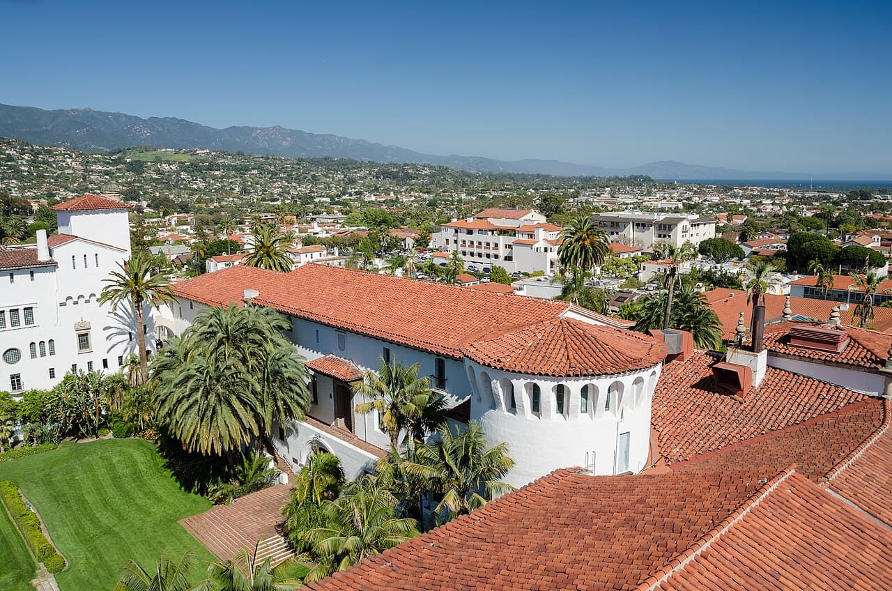 Red-tiled courthouse roofs, palm trees and Santa Barbara neighborhoods extending toward the mountains and coast.