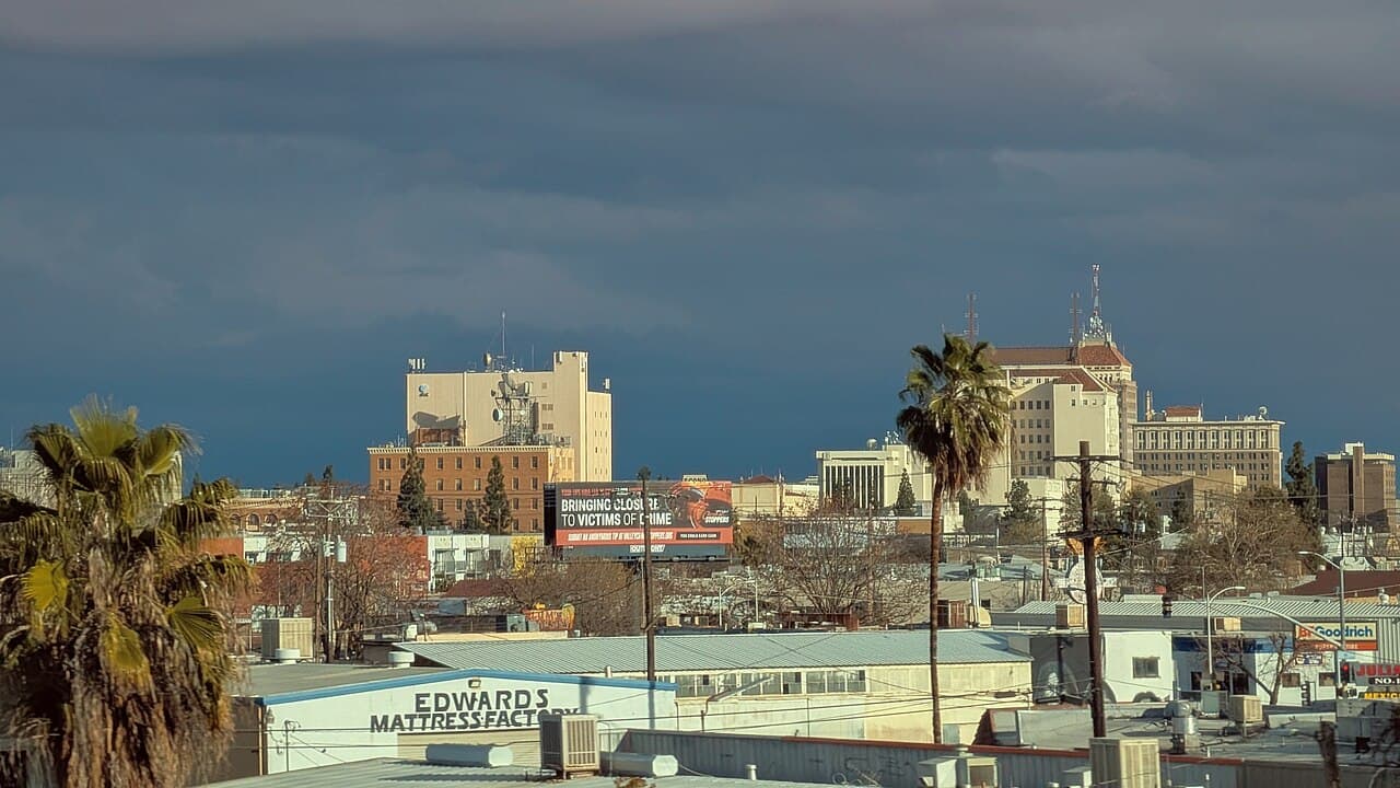 Downtown Fresno skyline and commercial buildings beneath a cloudy sky.